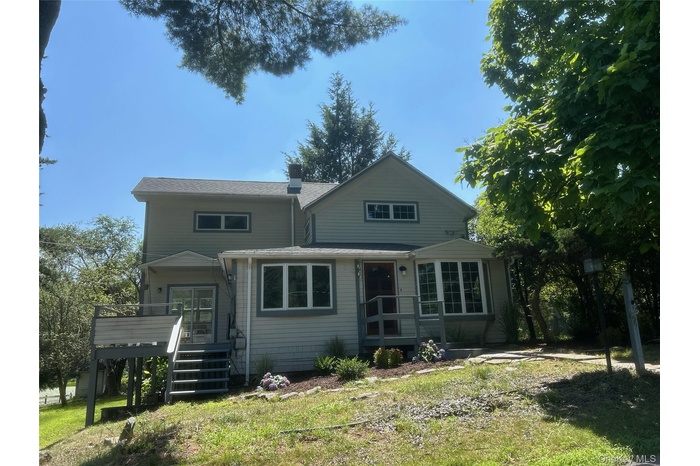 Front of property featuring stairway, a yard, a chimney, and roof with shingles