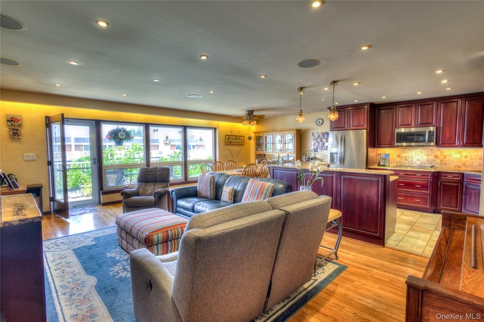 Living area with light wood-type flooring, recessed lighting, and a ceiling fan