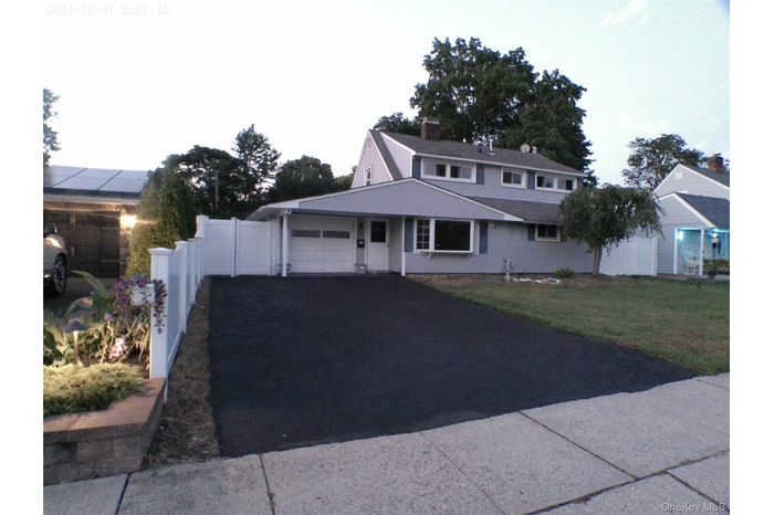 View of front of home with a garage, a porch, and asphalt driveway