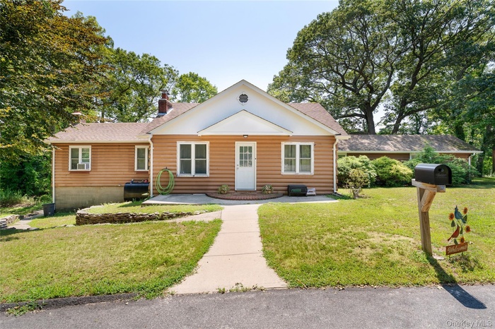 View of front facade featuring a front yard, faux log siding, a chimney, and a shingled roof