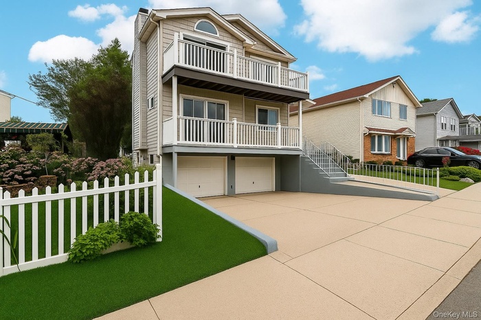 View of front of home featuring a garage, driveway, and a balcony