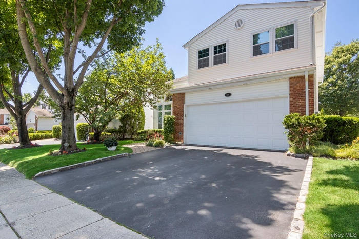 Traditional home with a garage, driveway, brick siding, and a front lawn