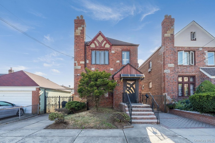 View of front of house featuring a chimney and brick siding