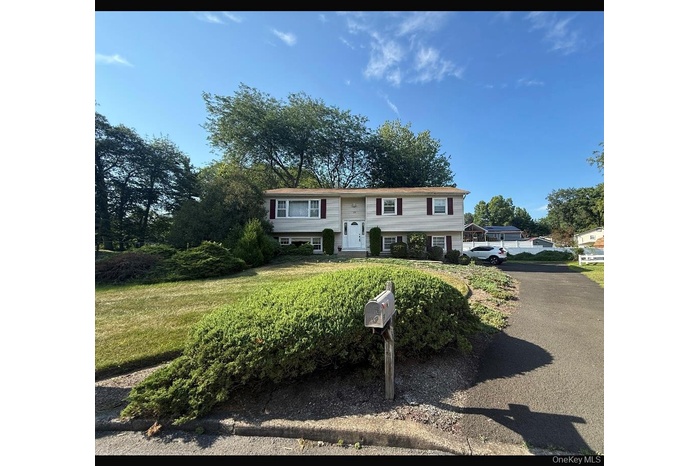 Raised ranch with asphalt driveway and a front yard