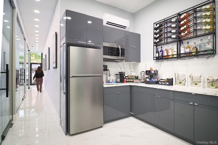 Kitchen with gray cabinetry, stainless steel appliances, light marble finish floors, modern cabinets, and a wall unit AC