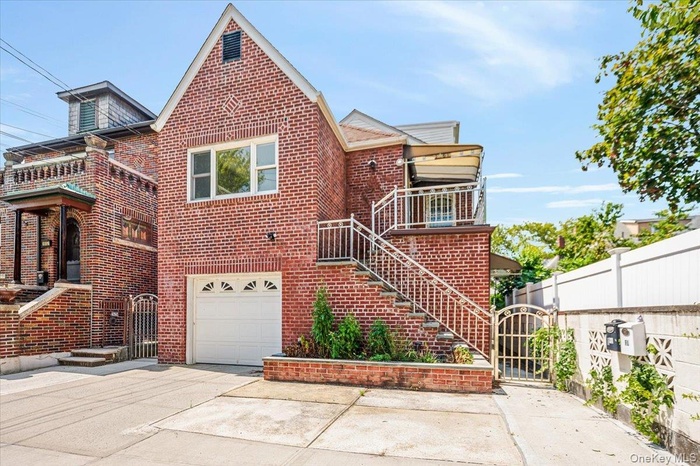 View of front of house featuring a gate, a garage, brick siding, and driveway