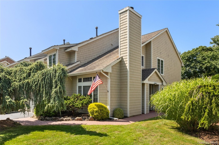 View of side of property featuring a shingled roof, a lawn, and a chimney