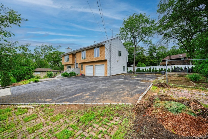 View of front facade featuring a garage, driveway, and a chimney