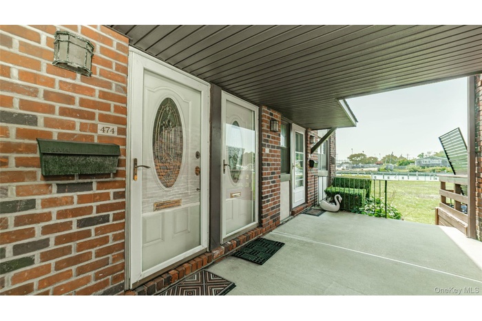 Entrance to property with covered porch and brick siding