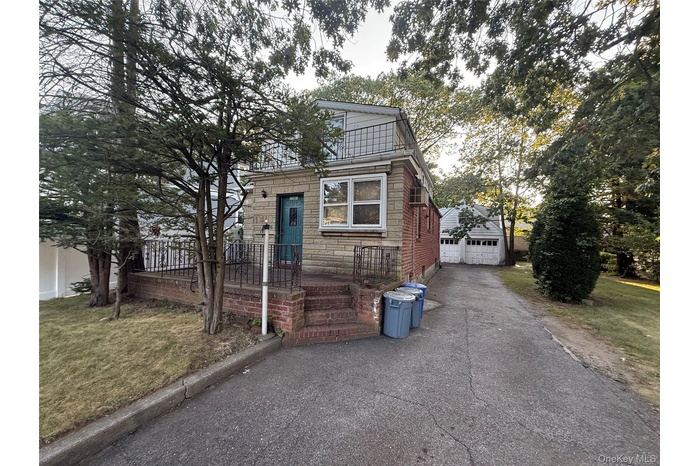 View of front of home featuring a large front yard, stone siding, asphalt driveway, and a two car garage.