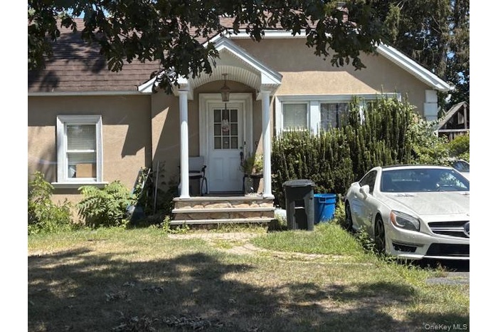 View of front of house with stucco siding and a front yard
