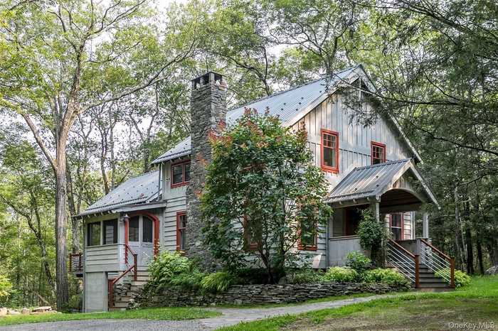 View of front of house with a metal roof, a chimney, stairs, and board and batten siding
