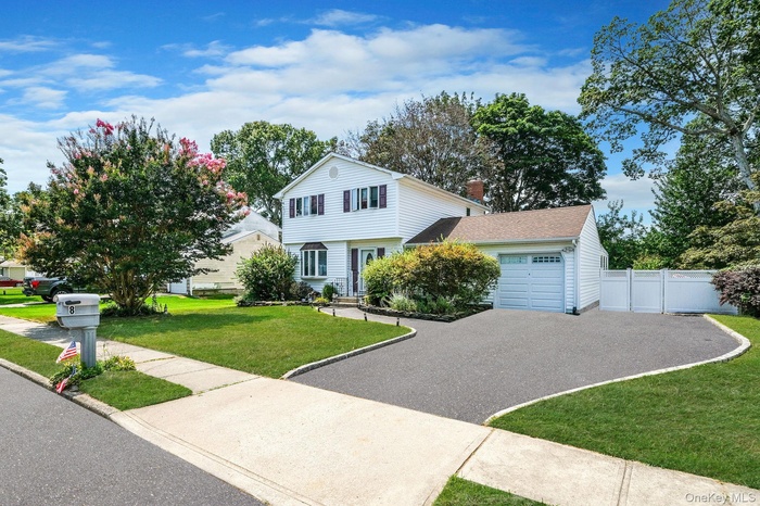 View of front of home with a garage, driveway, a chimney, and a shingled roof