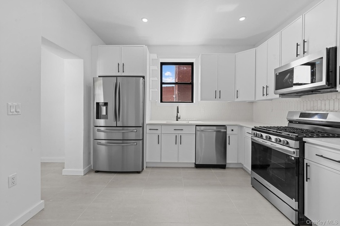 Kitchen with appliances with stainless steel finishes, white cabinets, light tile patterned flooring, recessed lighting, and backsplash