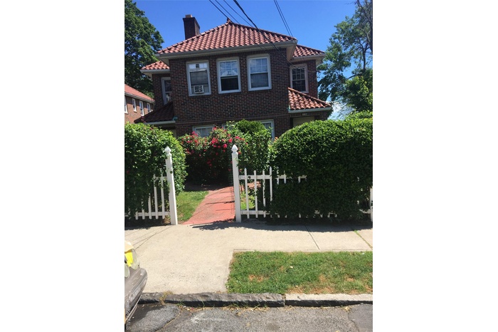 Mediterranean / spanish house with brick siding, a fenced front yard, a chimney, and a tiled roof