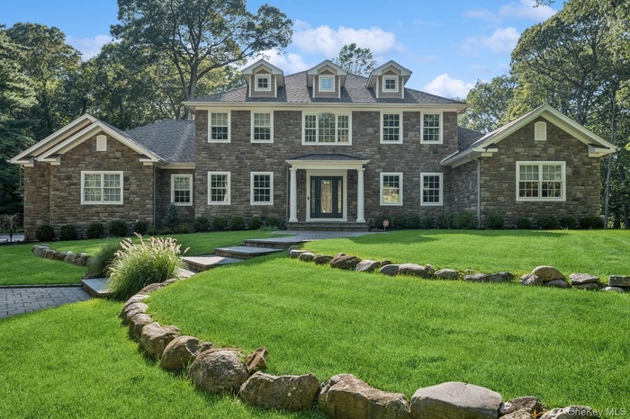 Colonial home featuring stone siding and a front yard