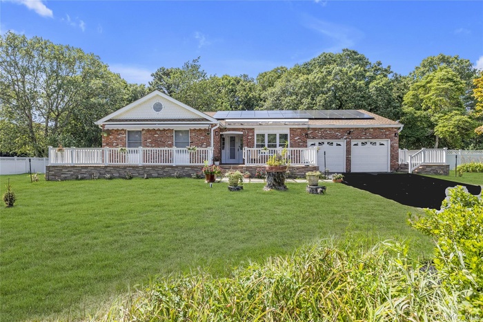Single story home with brick siding, a garage, solar panels, and driveway