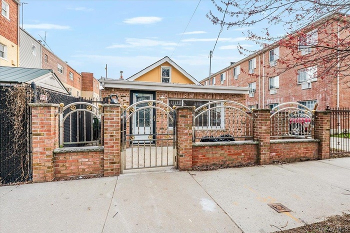 View of front facade with brick siding, a gate, and a fenced front yard