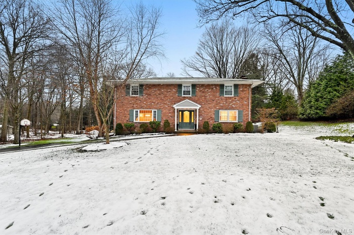 Colonial inspired home featuring brick siding and a chimney