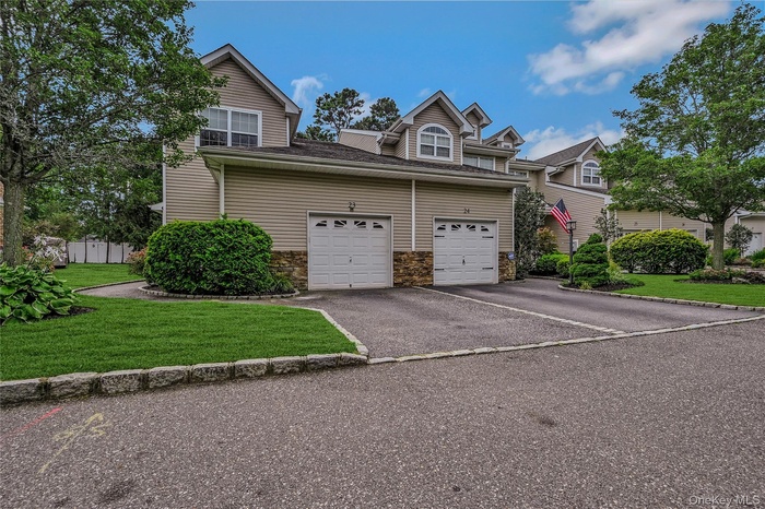 View of front facade featuring driveway, stone siding, and a front yard