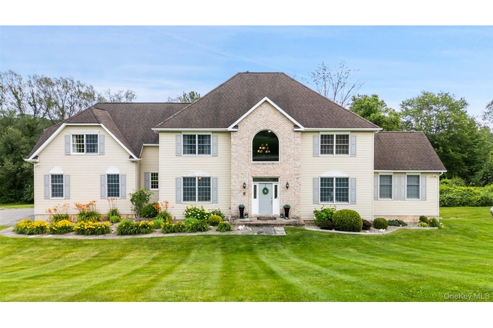 Colonial inspired home with a front yard and roof with shingles