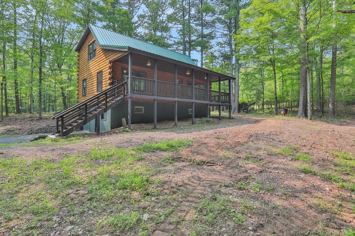 Back of house with stairs, log exterior, a metal roof, and covered porch