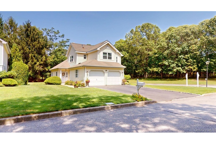 Traditional-style home featuring a front lawn, asphalt driveway, and a garage