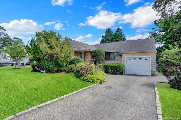 Ranch-style house with a garage, a front lawn, asphalt driveway, and roof with shingles