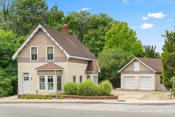 View of front of building featuring view of scattered trees, an outbuilding, a chimney, and a shingled roof