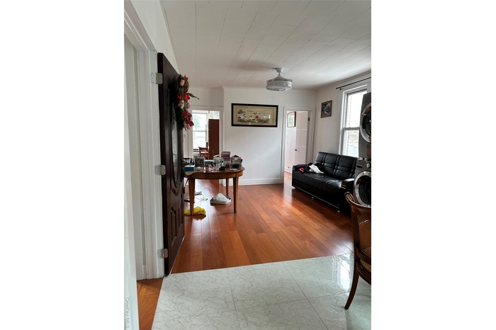 Living area with hardwood / wood-style floors and estacked washer and dryer