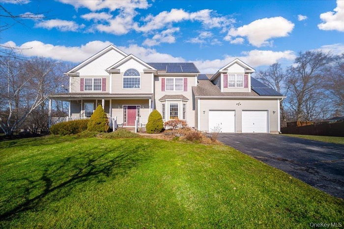 View of front of house featuring roof mounted solar panels, driveway, a front yard, and a porch