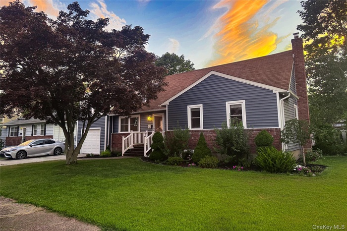 View of front facade with brick siding, a front yard, a chimney, an attached garage, and a shingled roof