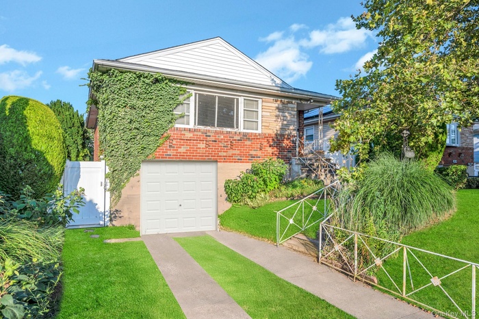 View of front of home featuring a gate, a garage, concrete driveway, and brick siding