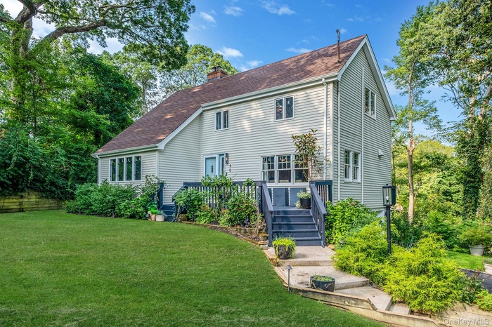 Back of property featuring a chimney, a lawn, and a shingled roof