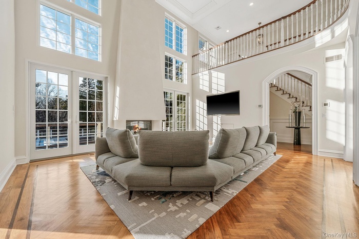 Living room featuring a glass covered fireplace, visible vents, arched walkways, and baseboards