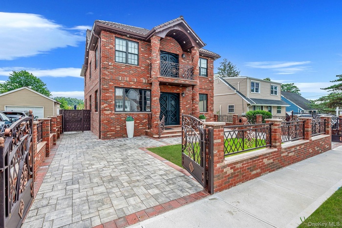 View of front of home with a gate, brick siding, a balcony, and a fenced front yard