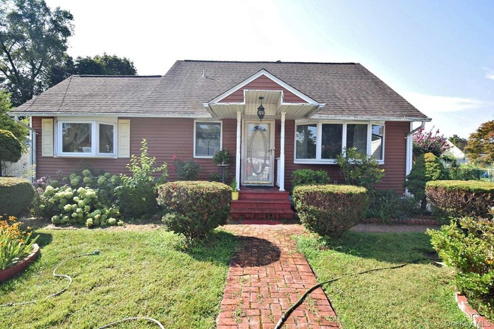 View of front facade with a front lawn and a shingled roof
