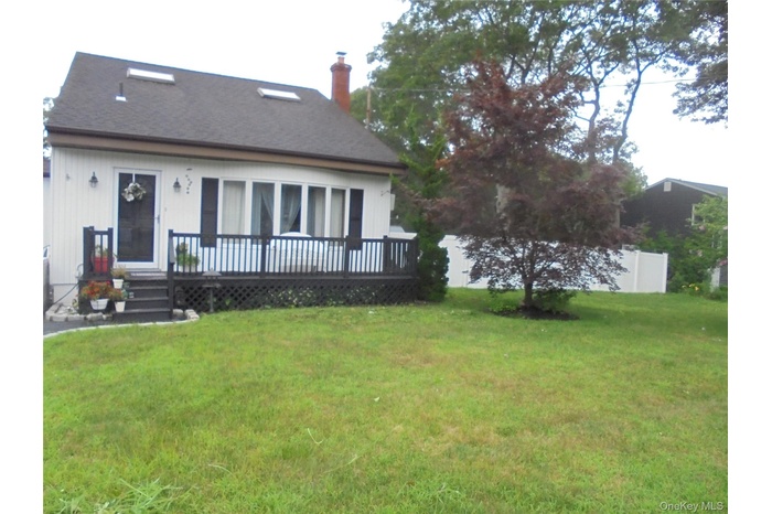 Rear view of property featuring a wooden deck, a chimney, and roof with shingles