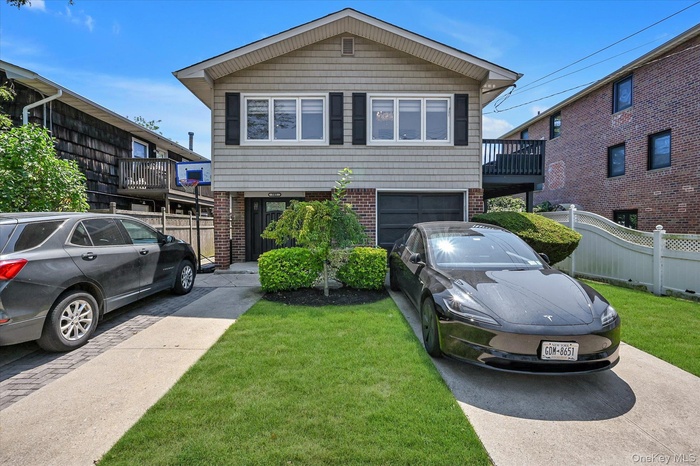 View of front of property with driveway, brick siding, a balcony, and an attached garage
