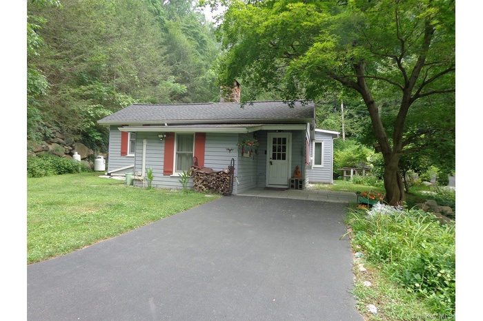Exterior home view,  featuring asphalt driveway, a front yard, a chimney and newer roof