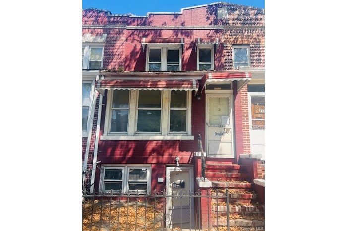 View of front facade featuring brick siding and a fenced front yard