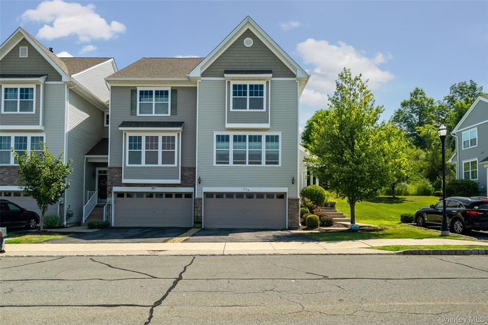 Craftsman-style home with an attached garage, brick siding, driveway, and stairs