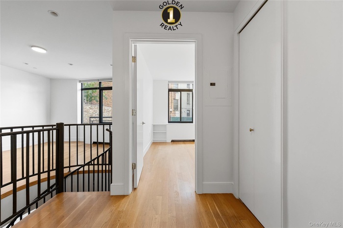 Hallway with an upstairs landing and light wood-style floors