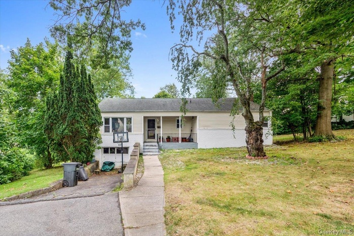 Single story home with a porch, a front yard, a garage, asphalt driveway, and brick siding