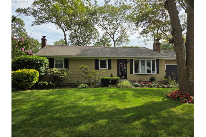 Ranch-style home featuring a chimney, a front lawn, and an attached garage