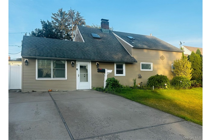 View of front facade with roof with shingles, a chimney, and a front yard