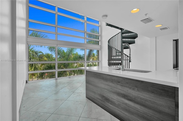 Double-height ceiling loft with modern kitchen, stainless steel appliances, spiral staircase, and mezzanine level. Bright, airy, and perfect for relax