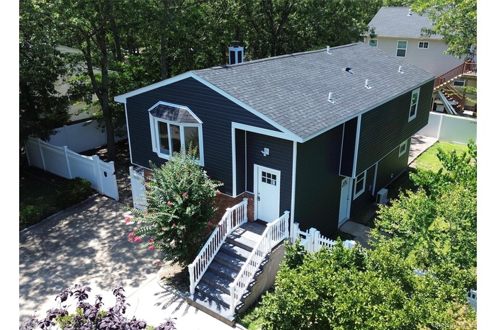 Bird's eye view of front and side of home featuring premium vinyl and brick siding, driveway, and a gate