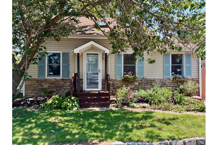 View of front of home with stone siding and a front yard