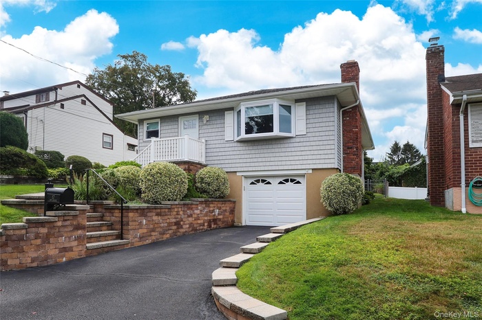 View of front of home with an attached garage, asphalt driveway, and a chimney